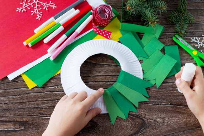 gluing green paper strips to paper plate